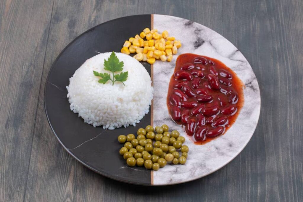 A plate divided into sections: white rice topped with cilantro, corn, green peas, and kidney beans in sauce.